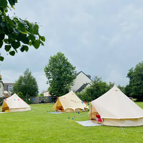 Canvas bell tents pitched on a lawn for an outdoor celebration