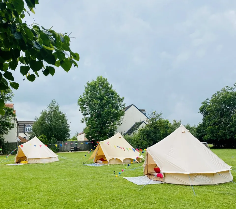 Three canvas bell tents set up on a lawn for an outdoor event